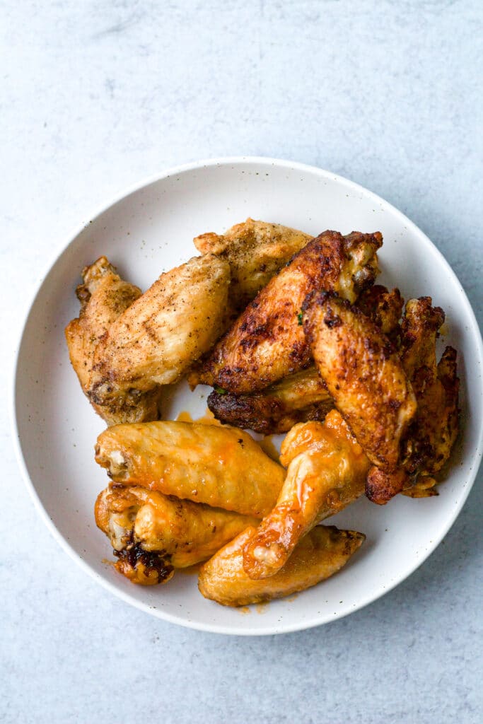 Three flavors of air fryer frozen chicken wings on plate.