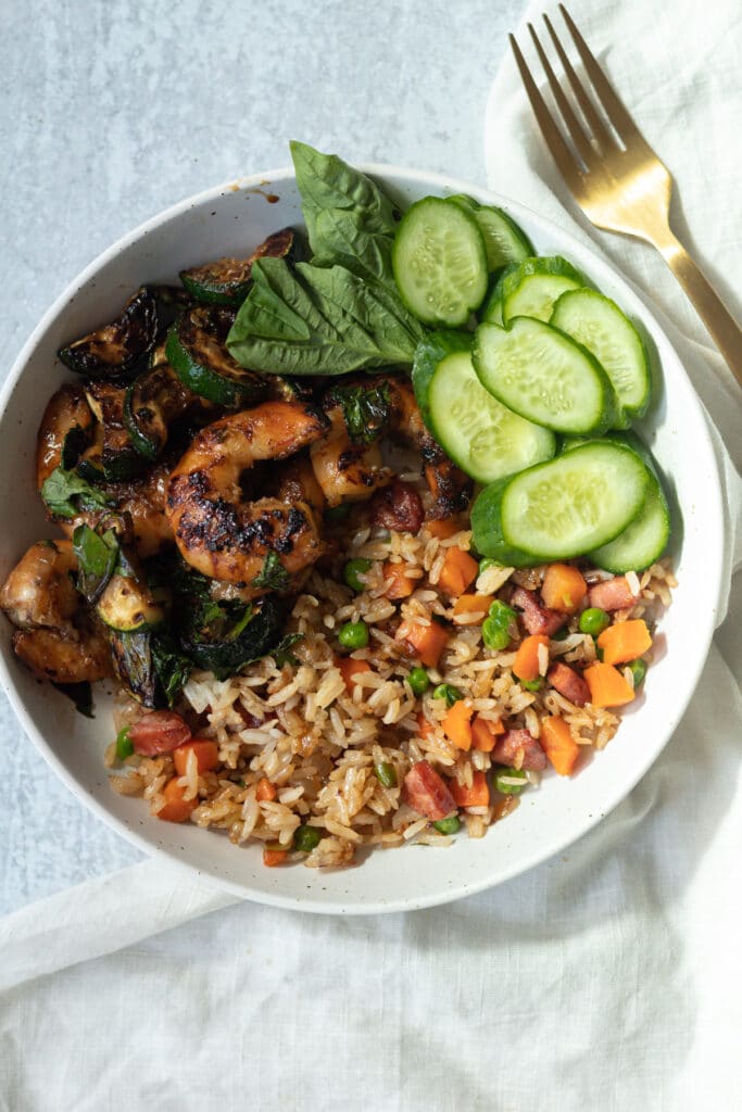 Plate with fried rice and meal on table with fork and napkin.