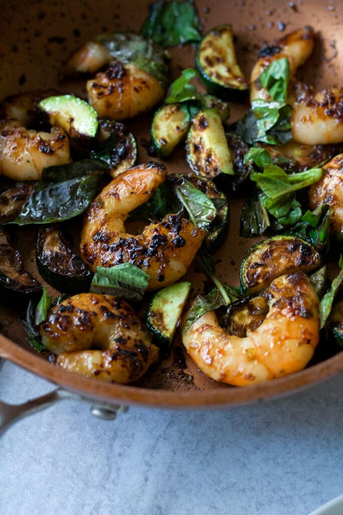 Shrimp, zucchini and basil in pan.