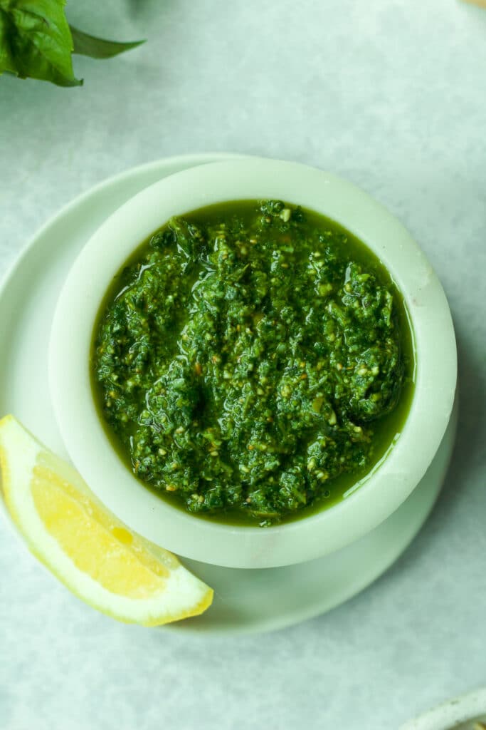 Nut-free pesto in small bowl with lemon wedge.