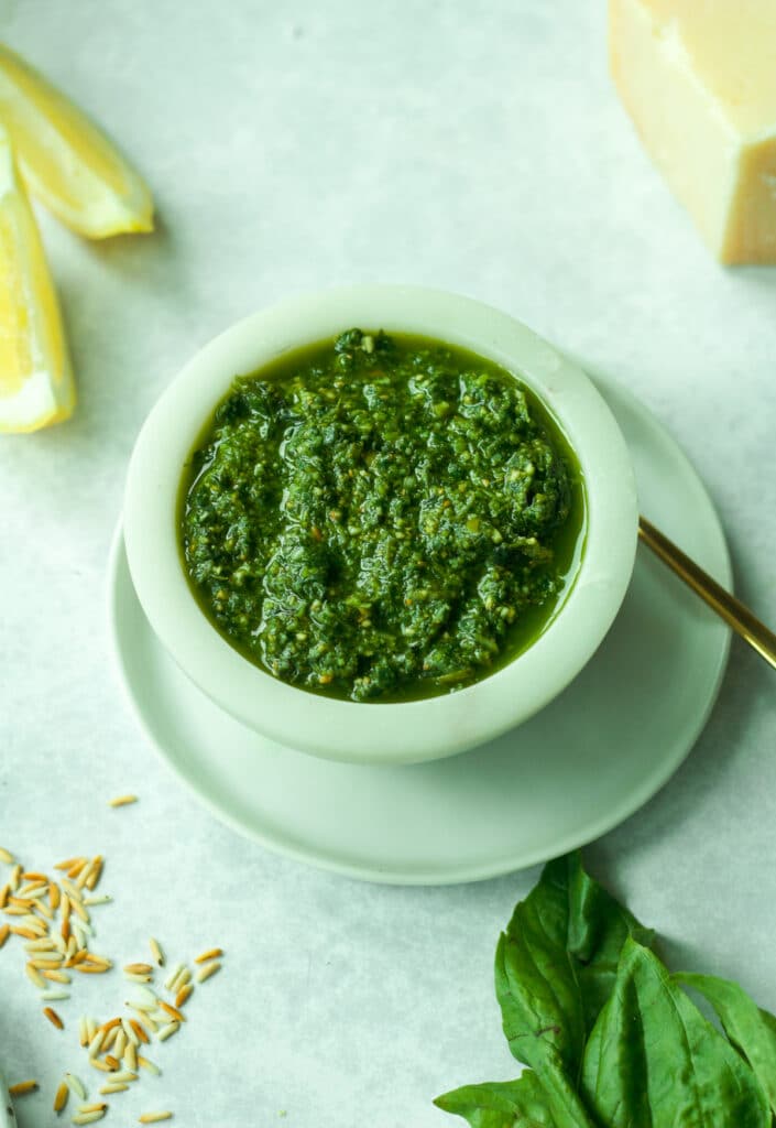 Small bowl of nut-free pesto on plate with fresh basil.