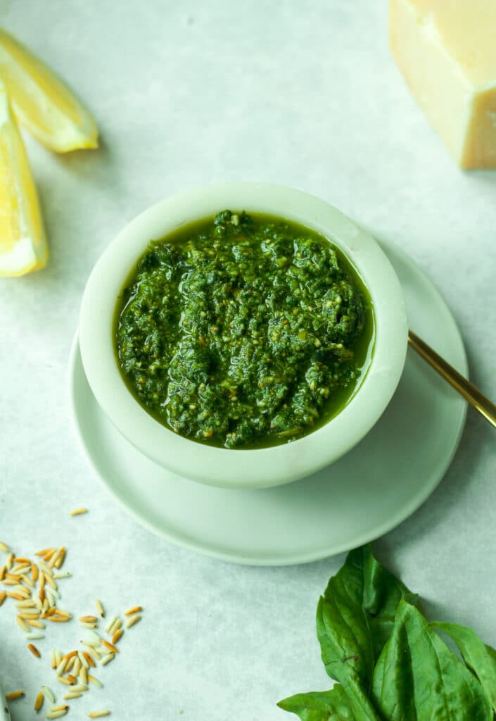 Small bowl of nut-free pesto on plate with fresh basil.