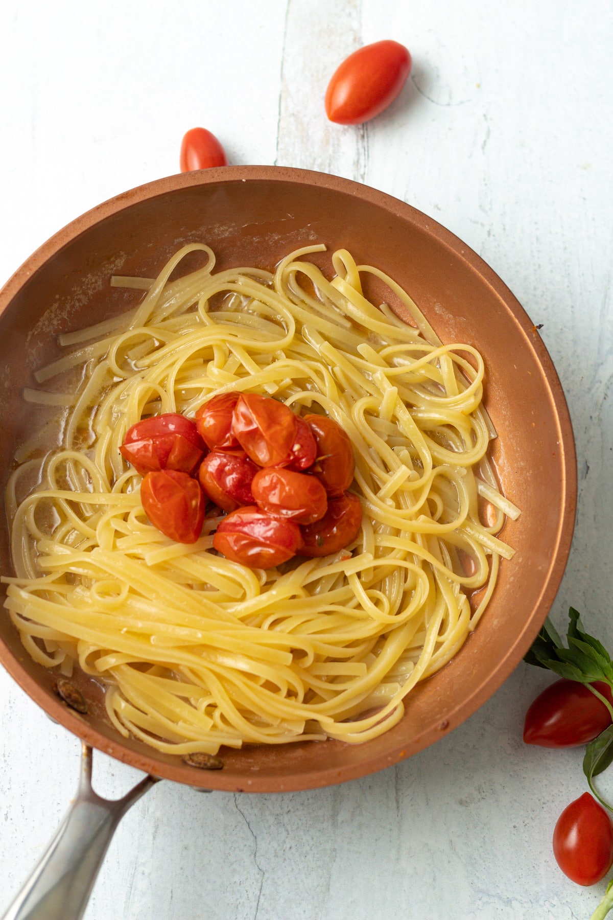 Partially cooked pasta with tomato confit in pan.