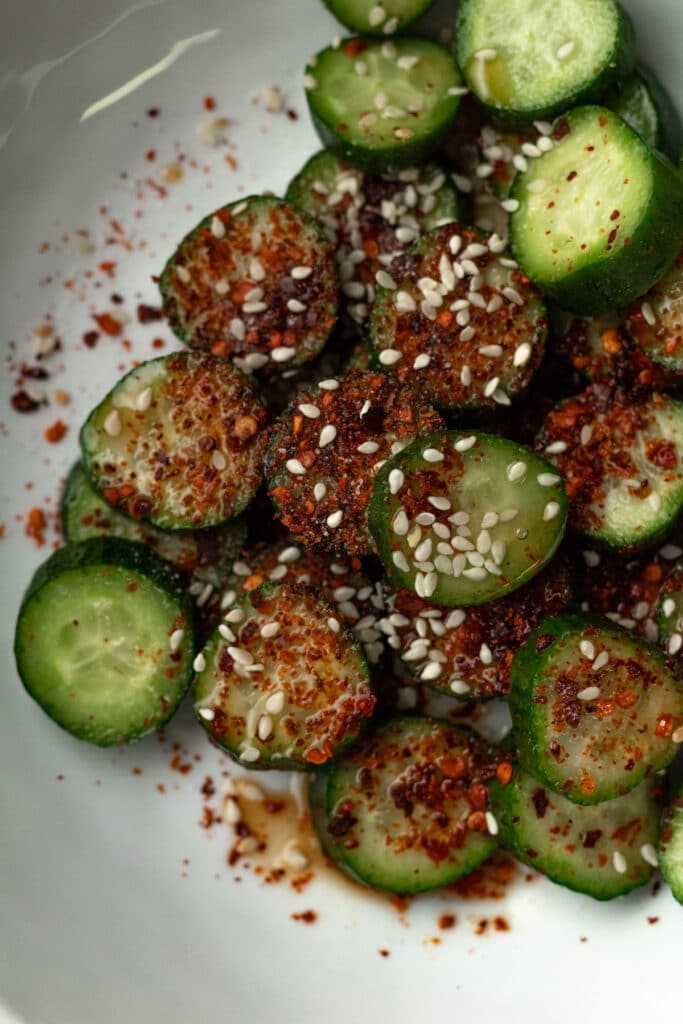 Chili flakes on cut up cucumber on plate.