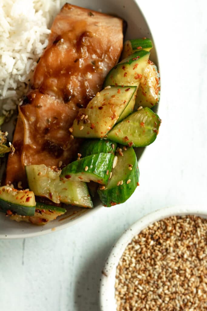 Spicy asian cucumber salad with salmon on plate.