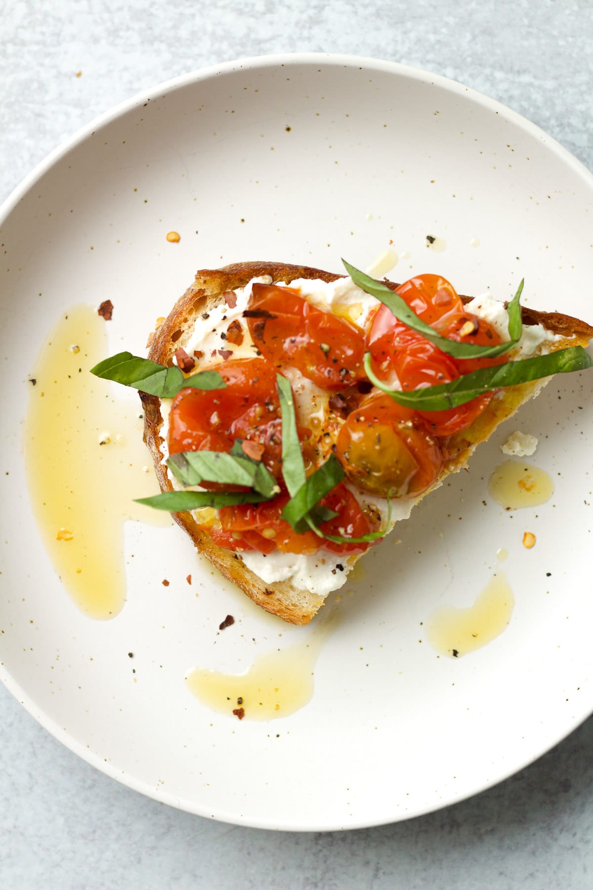 Toast with ricotta and tomato confit on plate.