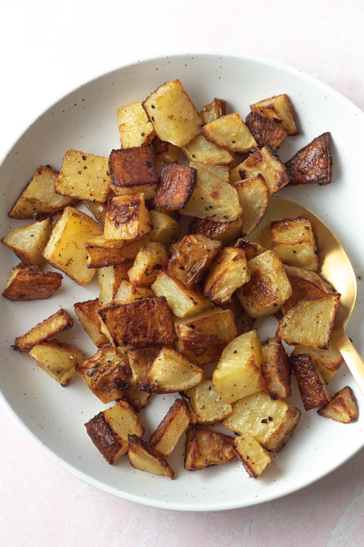 Roasted potatoes in bowl with serving spoon.