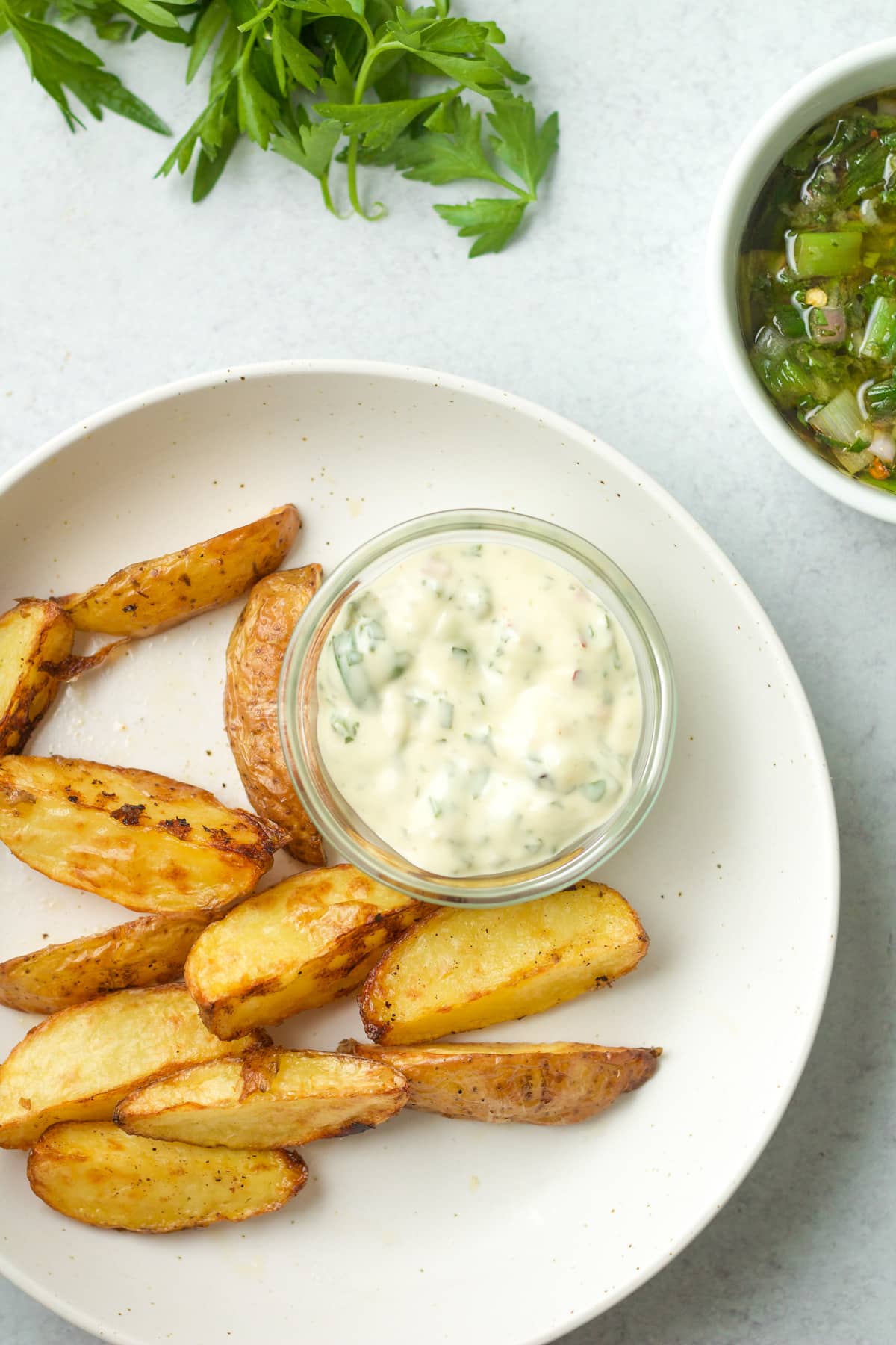 Plate of roasted potato wedges and bowl of chimichurri dip.