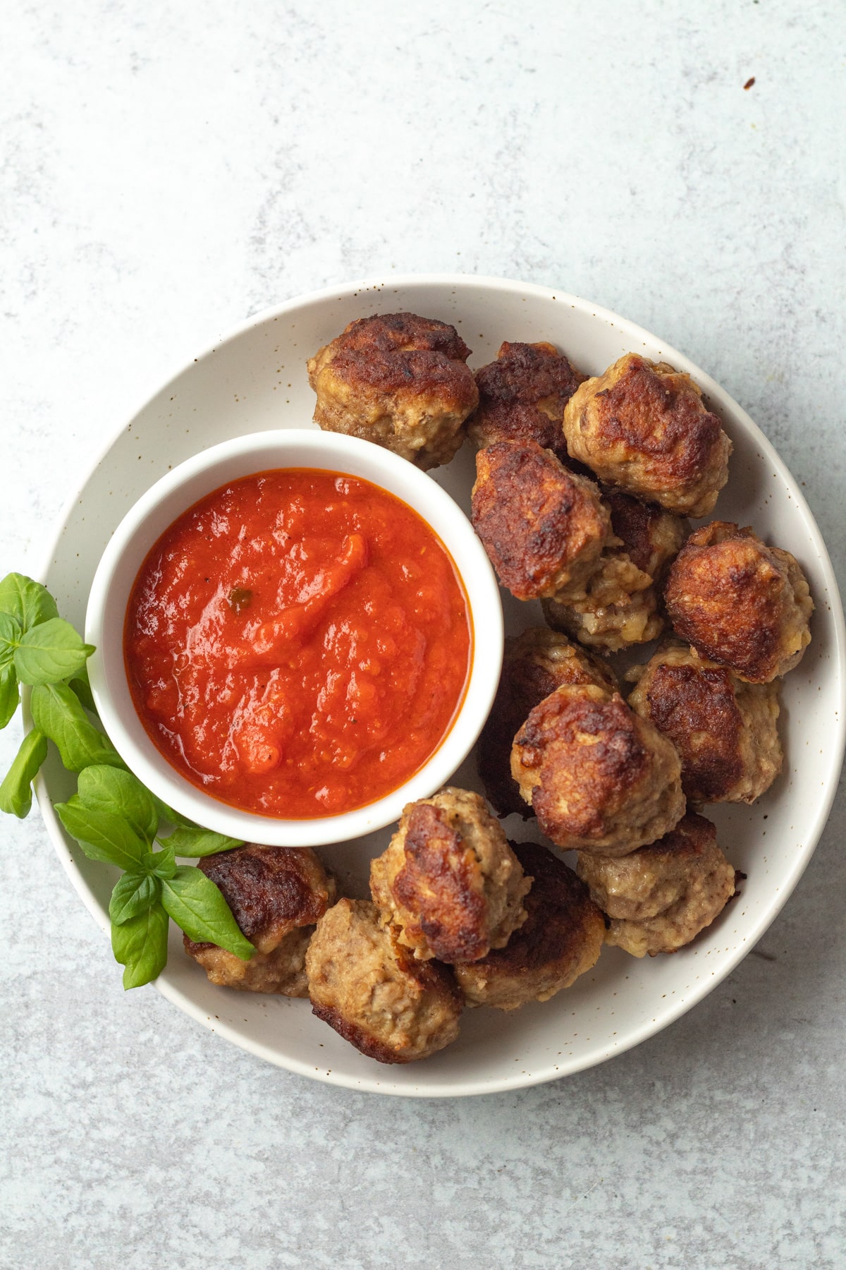 Plate of instant pot turkey meatballs with marinara sauce in small bowl.