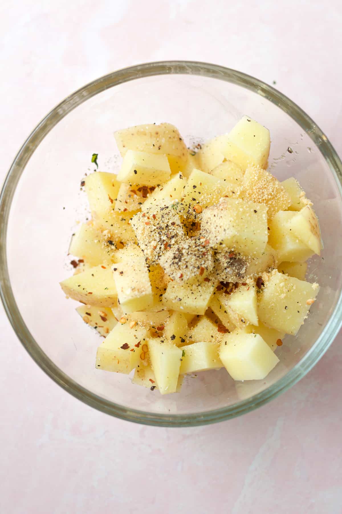 Cut raw potatoes in glass bowl with seasonings.
