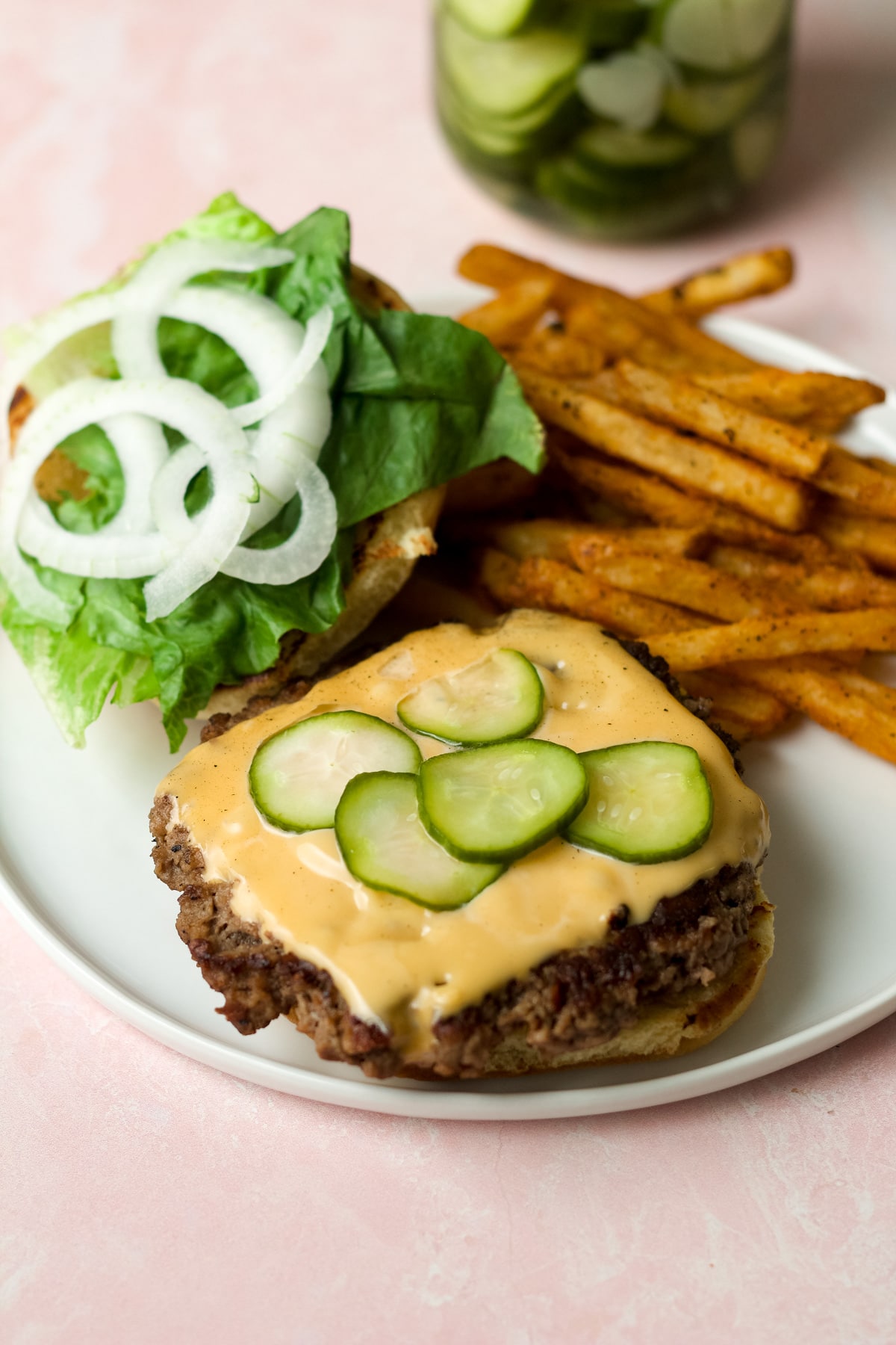 Burger and fries on plate with refrigerator dill pickles.