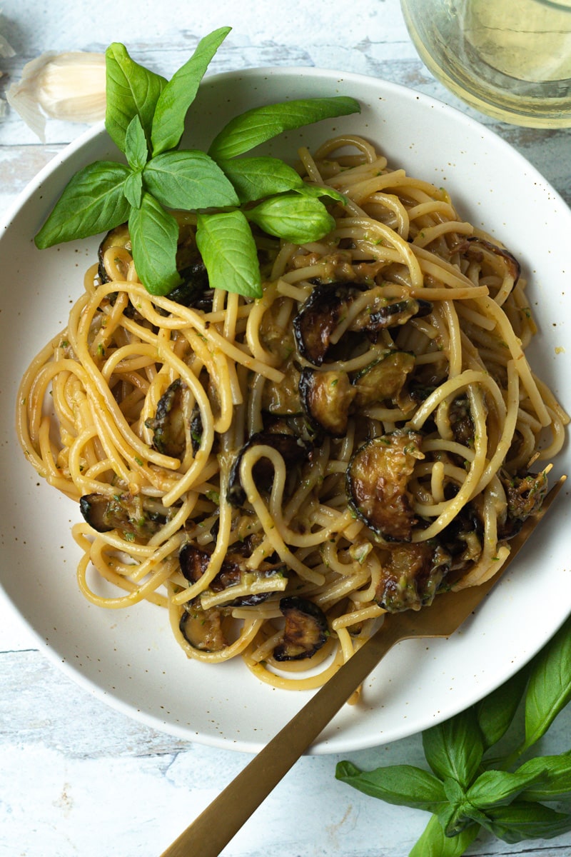 Spaghetti with zucchini in bowl with fork and basil garnish.