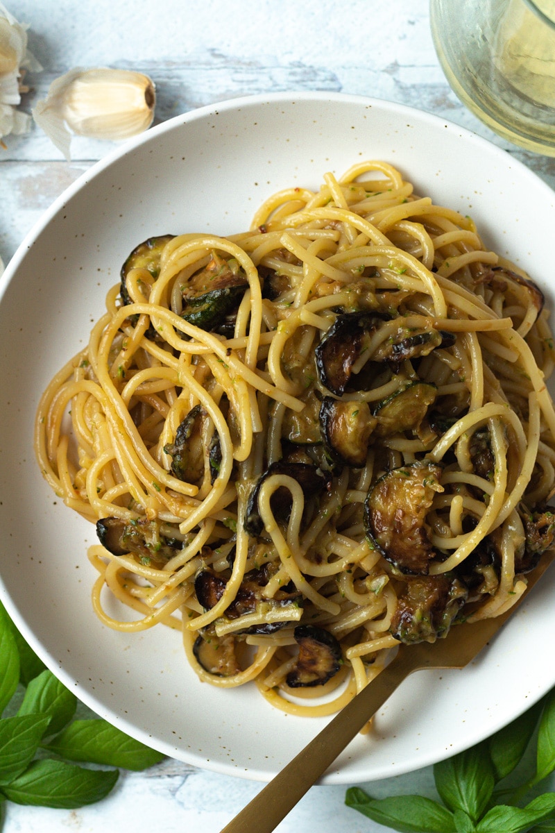 Close shot of pasta in bowl with basil and silverware.