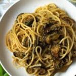 Spaghetti with zucchini in bowl with fork and basil.