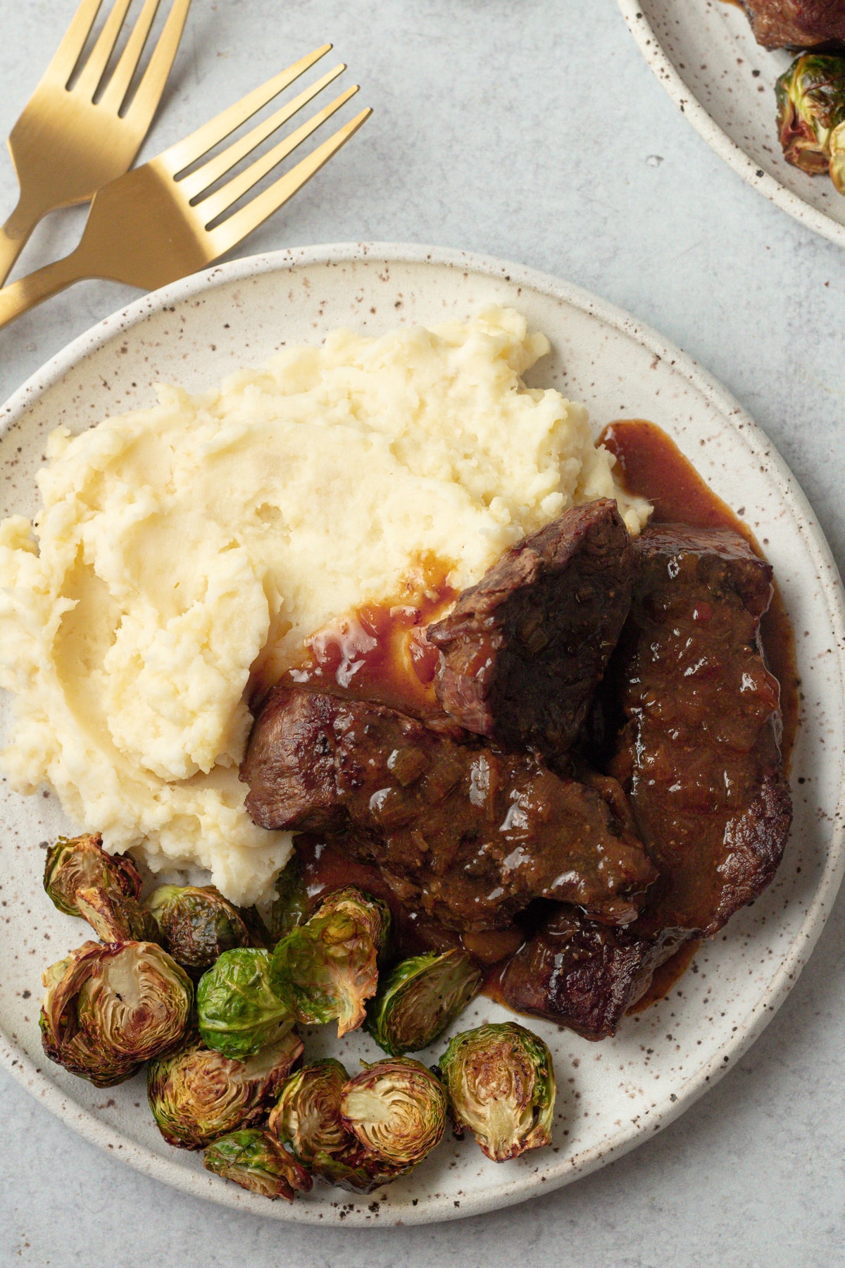 Small batch mashed potatoes on plate next to short ribs and roasted vegetable.