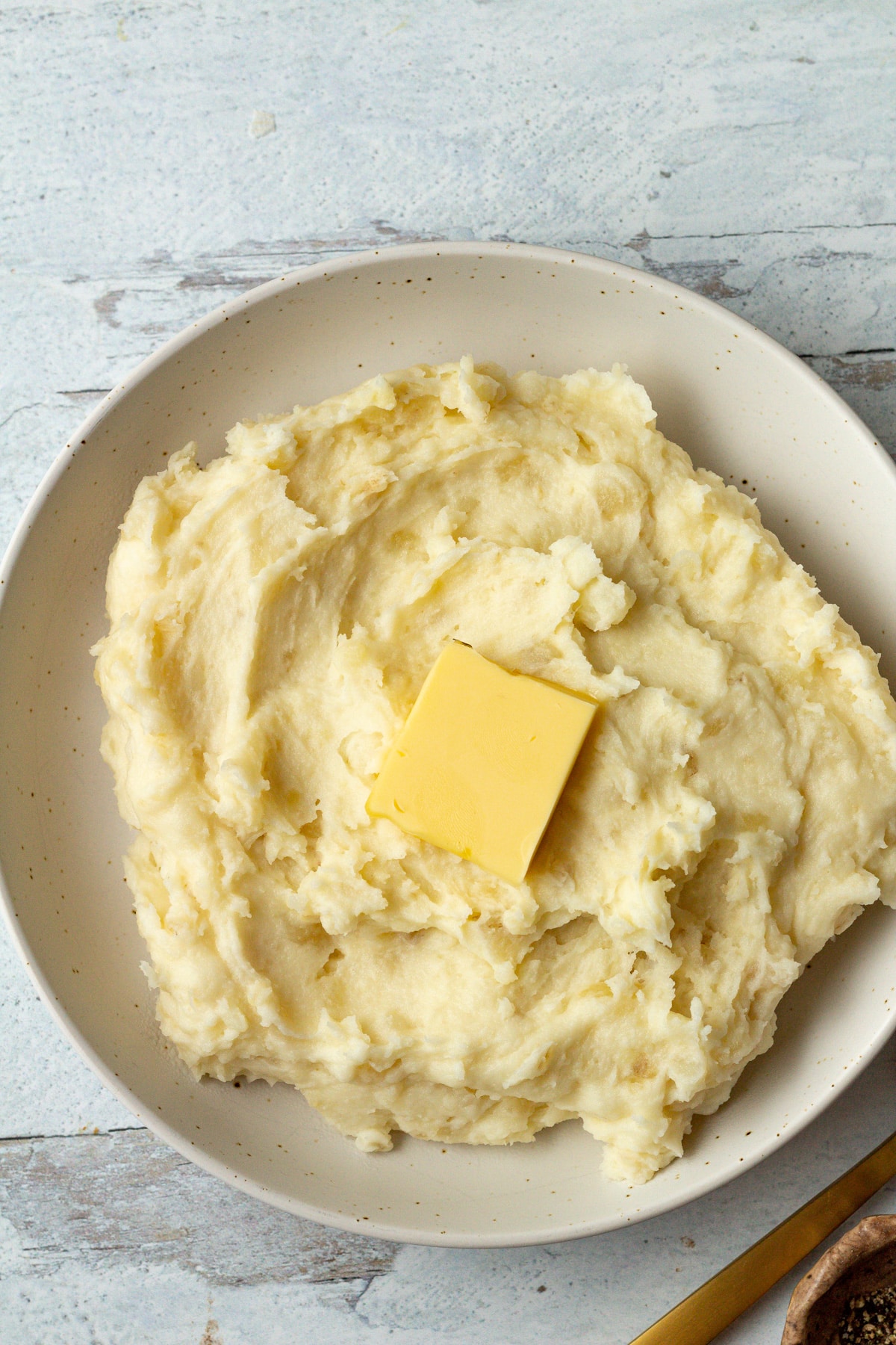 Pat of butter on top of mashed potatoes in bowl.