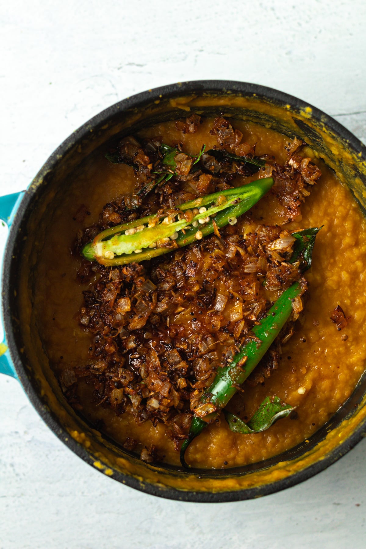 Cooked onions and spices with green chili on top of lentils.