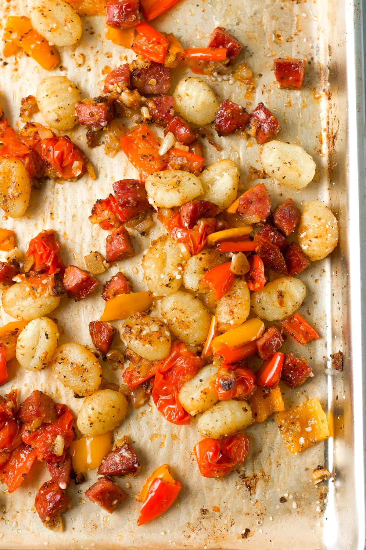 Cooked gnocchi, sausage and peppers on sheet pan.