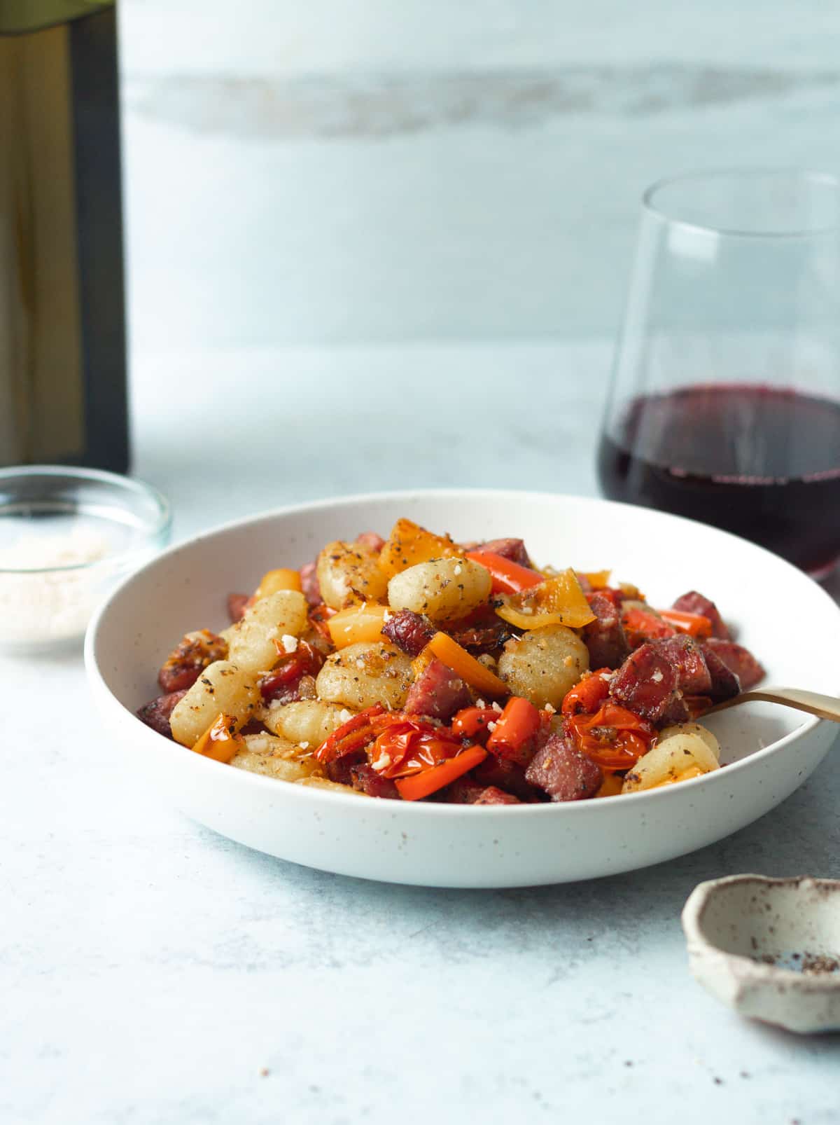 Table with bowl of pasta, glass of red wine and bottle of olive oil.