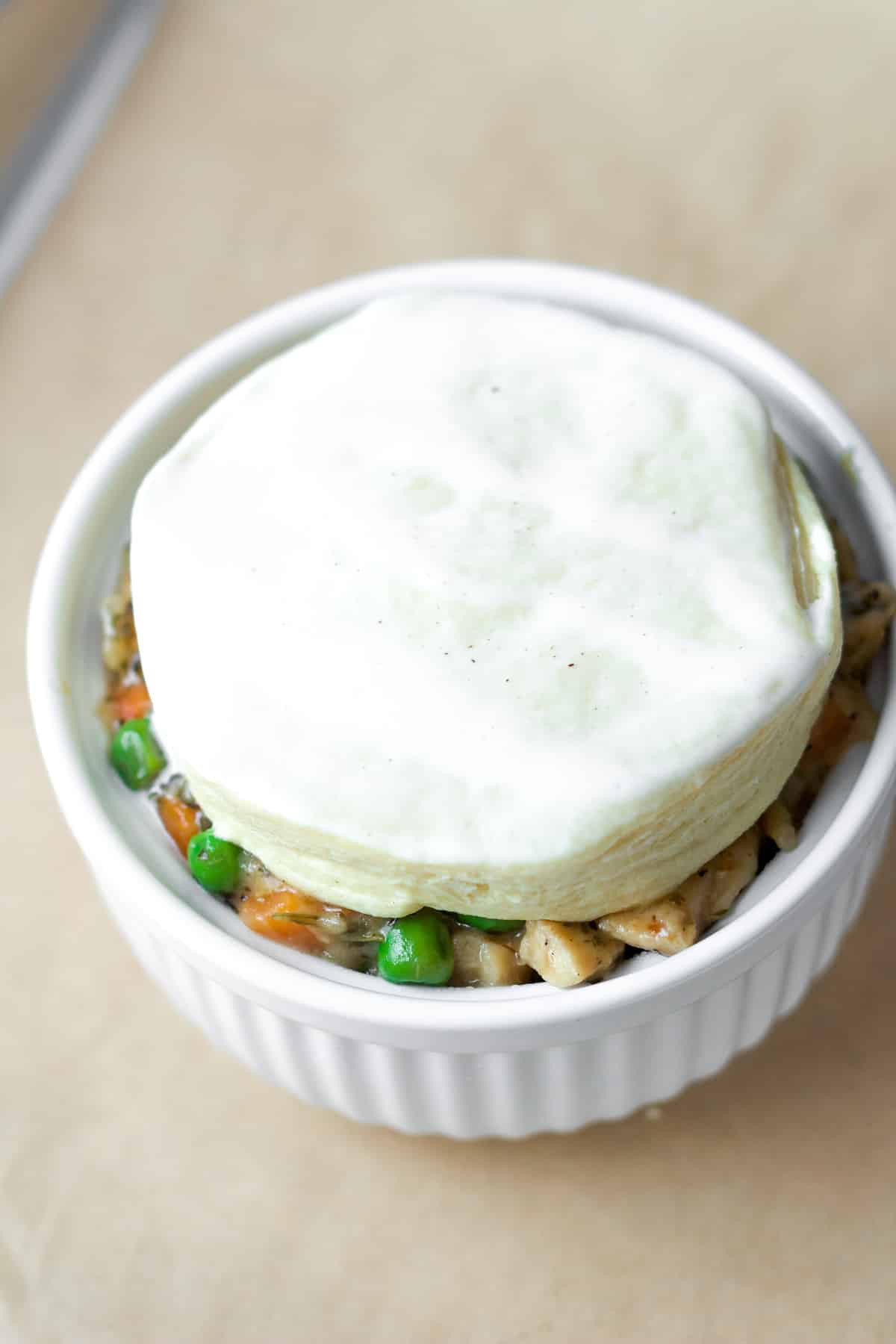 Filling and biscuit in ramekin before oven.